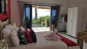 A bedroom with a bed, pillows, a wardrobe, and a view of the outdoors. - Nalini Resort (Karangasem)