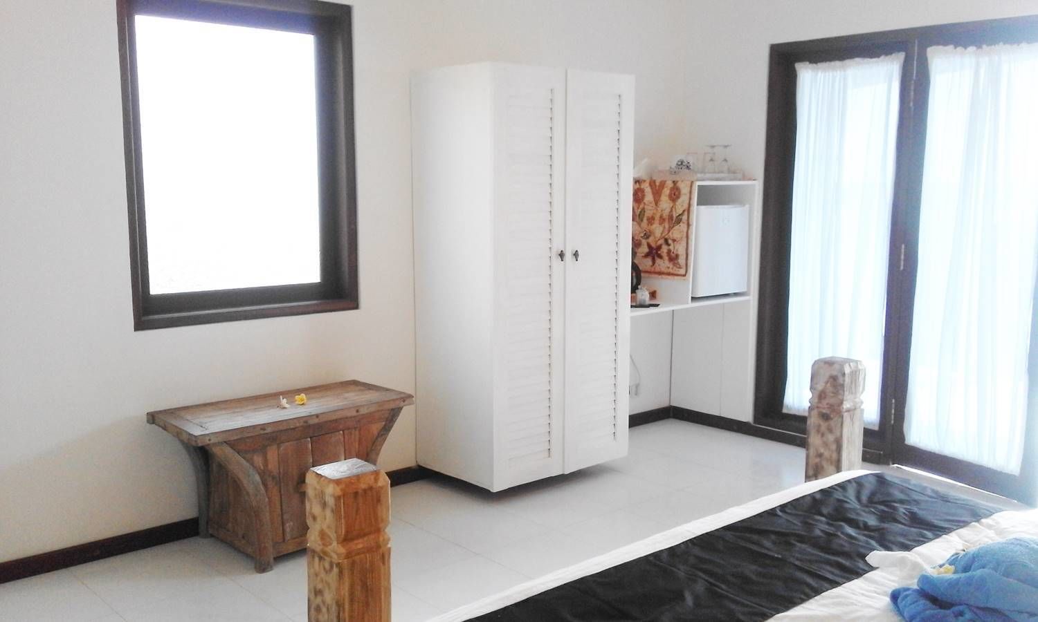 A bedroom with a bed, a wooden bench, a wardrobe, and a window.