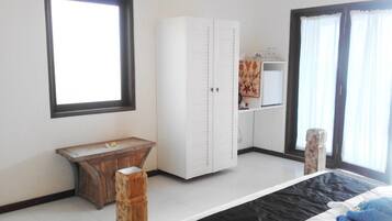 A bedroom with a bed, a wooden bench, a wardrobe, and a window.