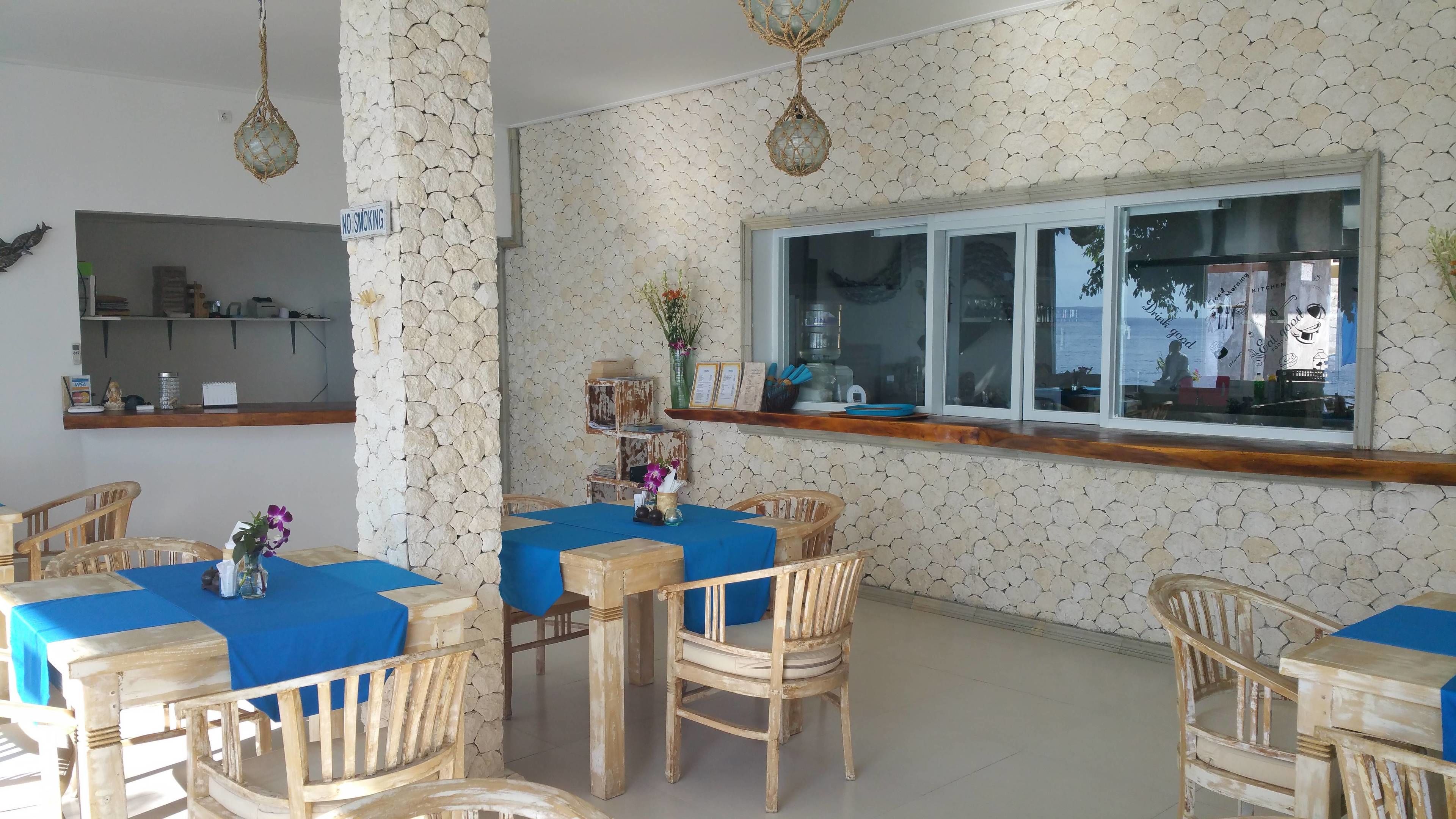 Un comedor con mesas cubiertas de manteles azules, sillas de madera y lámparas colgantes.