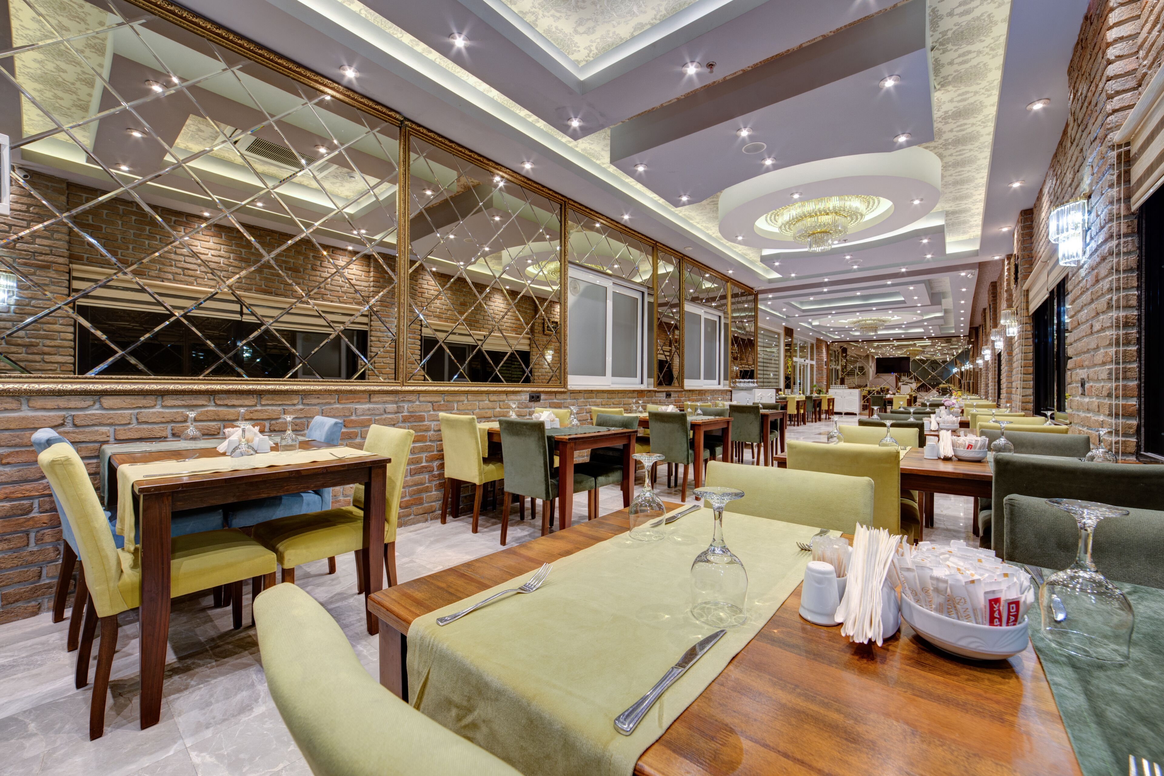 A restaurant with multiple dining tables, chairs, and a chandelier.