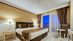 Een hotelkamer met een groot bed, een nachtkastje, een stoel en uitzicht op buiten.
