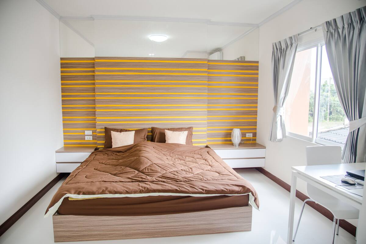 Un dormitorio moderno con una cama grande, una mesita de noche y un escritorio.