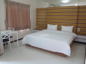 A hotel room with a bed, a desk, and a chair.