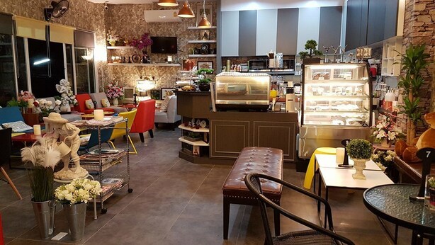 A cozy cafe with a counter, seating area, and decorative plants. - AAA Mansion (Hat Yai)