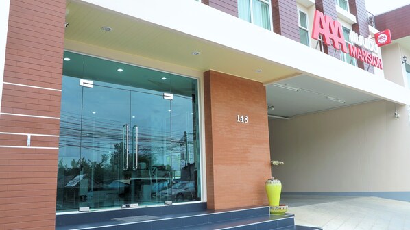 A modern building with a large glass entrance, a prominent address number '148', and a sign indicating 'NIDA MANSION'.