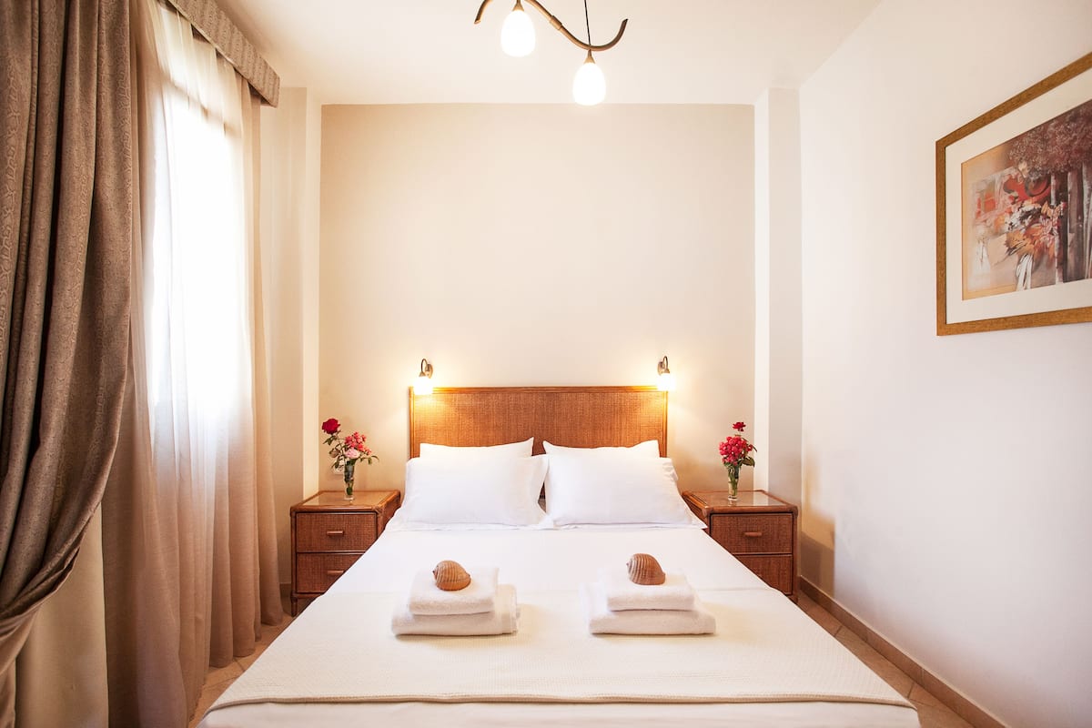 Habitación de hotel con una cama grande, dos mesitas de noche, un cabecero de madera y un cuadro en la pared.