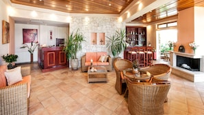 A spacious living area with a stone wall, wicker furniture, and a fireplace.