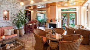 A spacious living area with a stone wall, wicker furniture, and a fireplace.