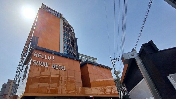 Un hôtel doté d’une façade orange bien visible et sur laquelle on peut lire l’inscription « SHOW HOTEL ».