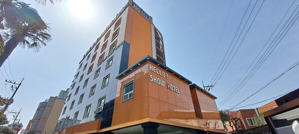 A hotel with a modern design, featuring a prominent 'HELLO SHOW HOTEL' sign on the facade.