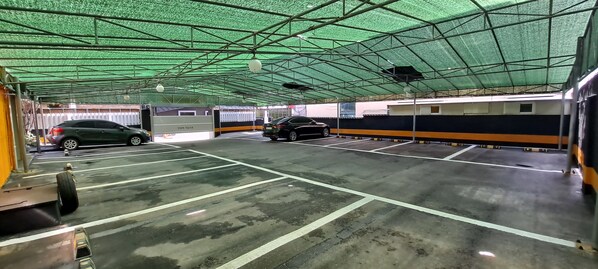 Un área de estacionamiento techada con varios automóviles y una máquina para boletos.