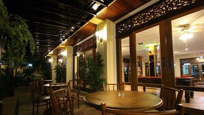 An indoor dining area with wooden tables and chairs, potted plants, and a ceiling fan. - I Boutique Hotel (Pluak Daeng)