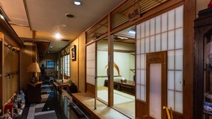En traditionell japansk inredning med tatamimattor på golvet, skjutdörrar och en receptionsdisk.