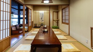Ett traditionellt japanskt rum med tatamimattor på golvet, ett lågt träbord, skjutdörrar och en shoji-skärm.