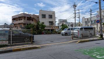 A street view with a building that has a sign for a business, a parked car, and a no parking sign.