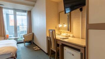 Une chambre d’hôtel équipée d’un lit, d’un bureau, d’une chaise et d’un téléviseur.
