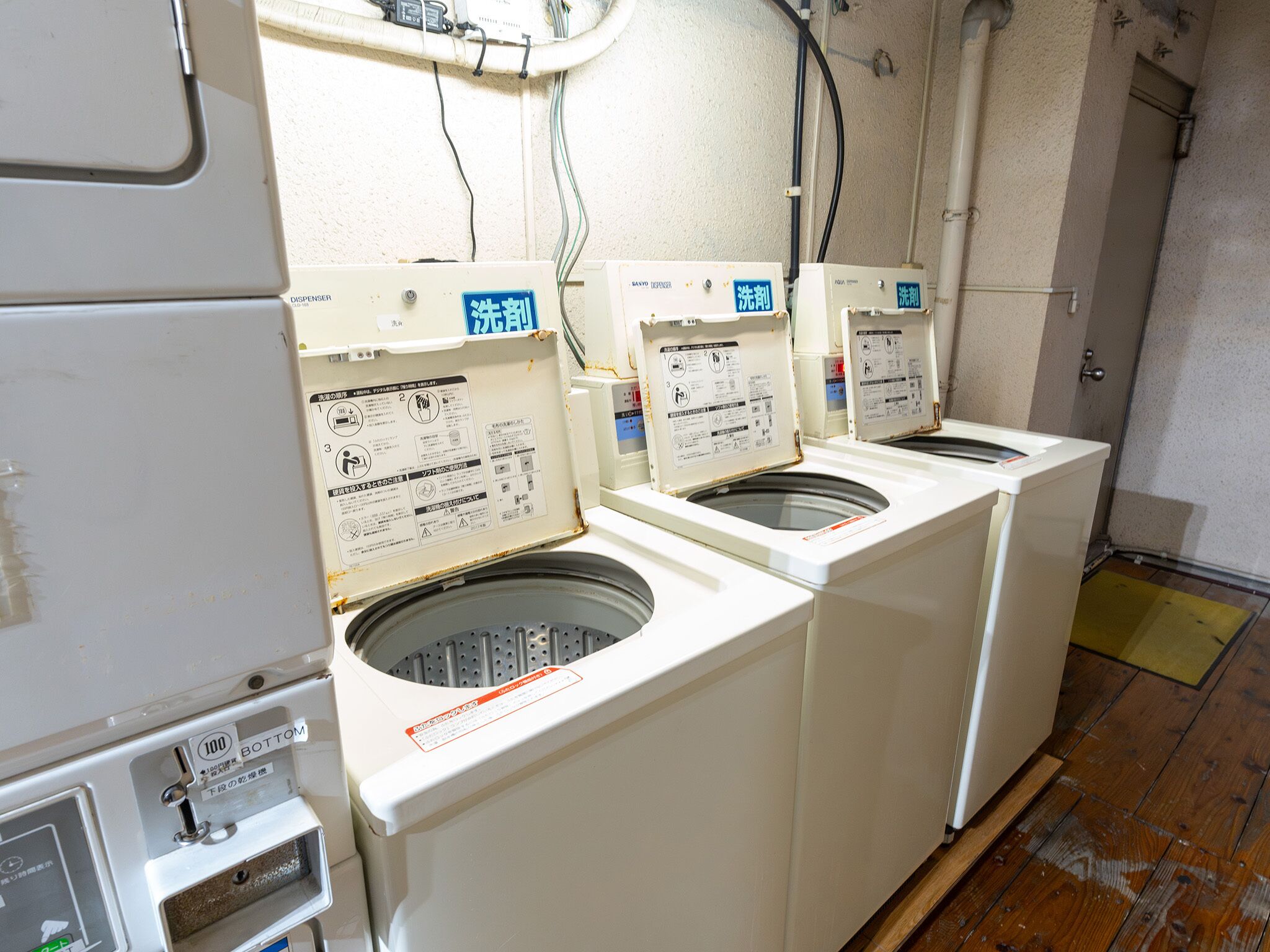A laundry area with two front-loading washing machines, a control panel, and a wall-mounted electrical panel.