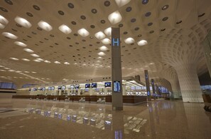 Una terminal aeroportuaria espaciosa con múltiples mostradores de registro, pantallas digitales de información de vuelos y un diseño de techo distintivo.