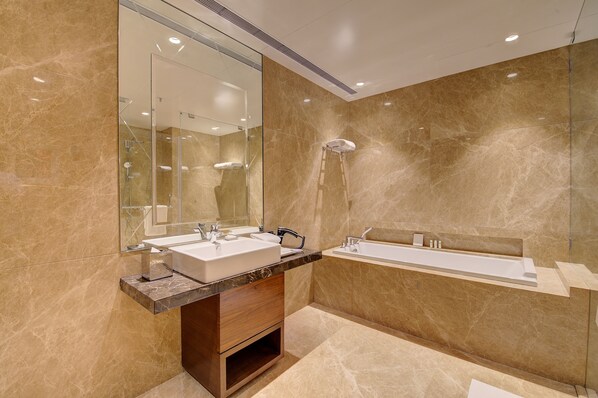 A modern bathroom with two sinks, a bathtub, and a large mirror.