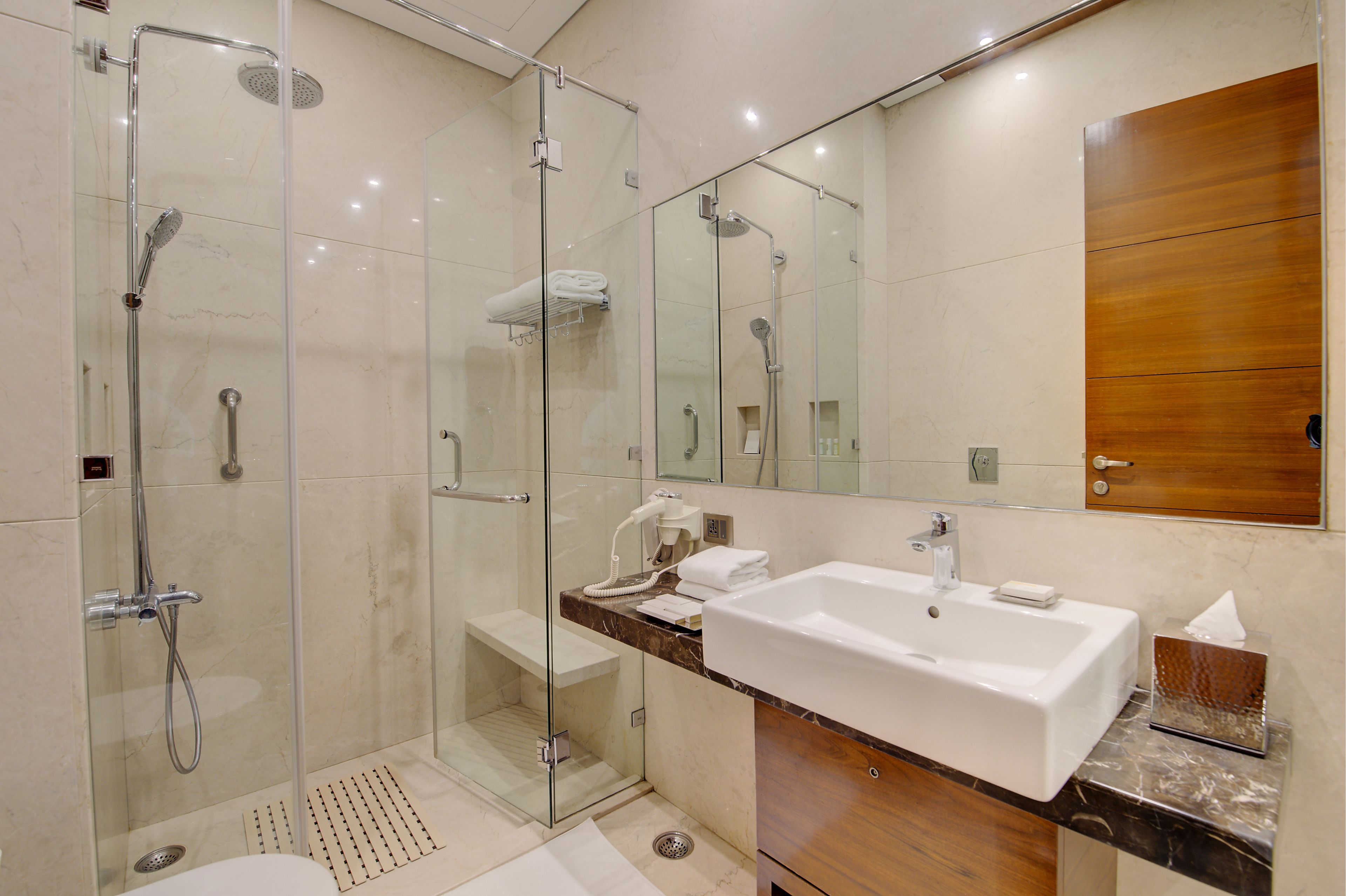 A modern bathroom with a glass-enclosed shower, a large sink, and a wooden vanity.