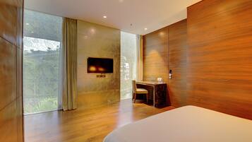 Een moderne hotelkamer met een groot bed, een bureau met stoel, een flatscreen televisie aan de wand en een groot raam met gordijnen.