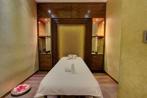 A hotel room with a long bed, wooden paneling, and a decorative wall with a geometric pattern.