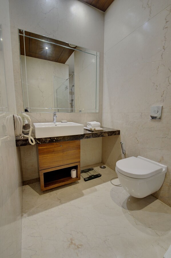 Un baño moderno con lavamanos de mármol, tocador de madera y un inodoro.