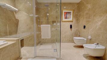 Un baño moderno con ducha envuelta en vidrio, bañera independiente y retrete.
