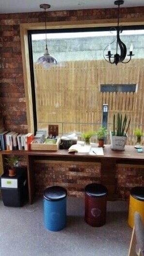 A room with a brick wall, a large window, a wooden desk with books and plants, and a hanging light fixture. - Nolewaluck (Gyeongju)