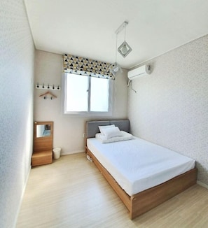 A small, modern bedroom with a single bed, a bedside table, a mirror, and a window with a geometric-patterned valance. - Nolewaluck (Gyeongju)