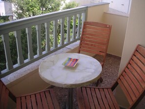 A small balcony with a round table and two wooden chairs. - Afrodite Hotel (Tinos)
