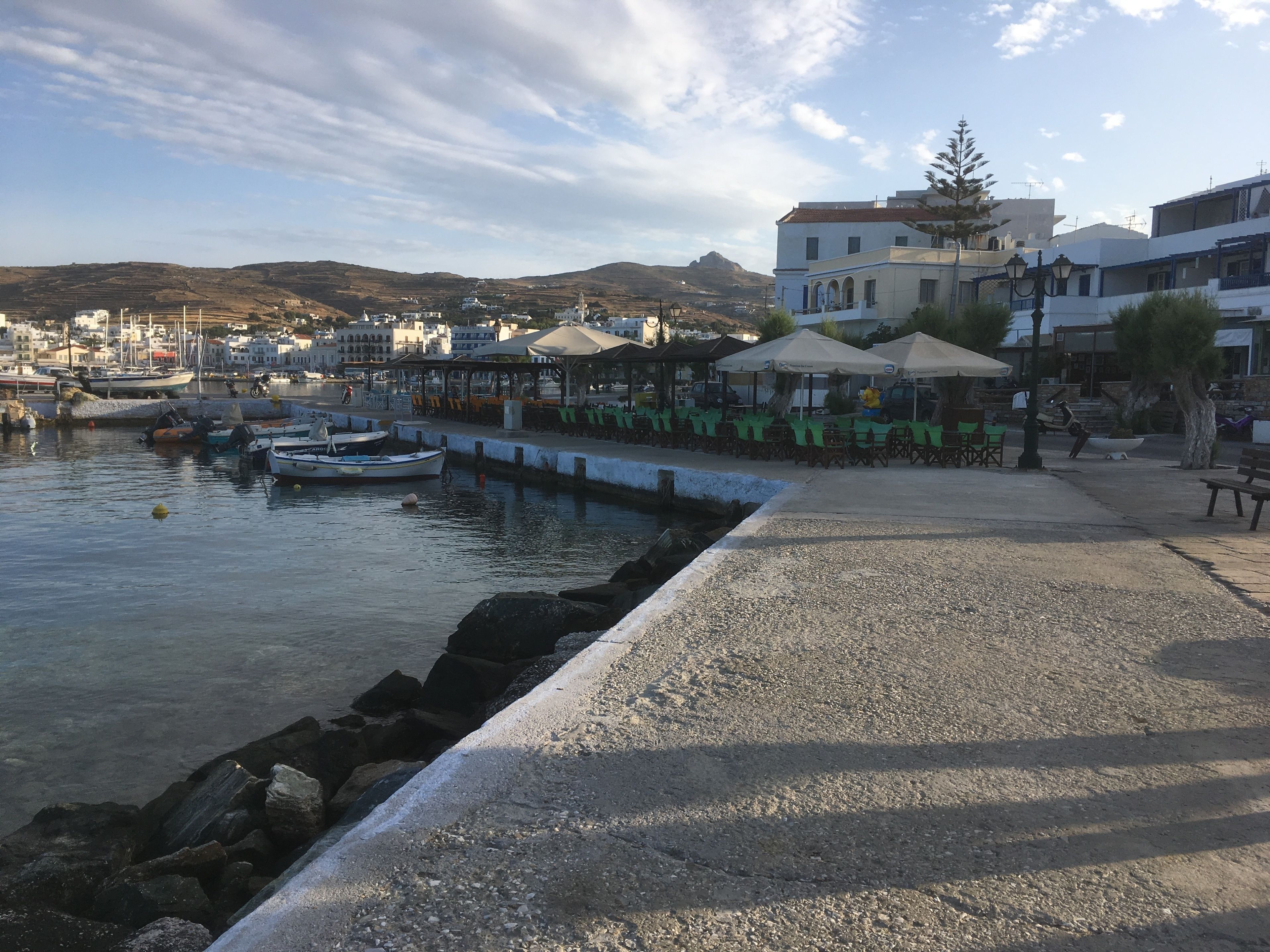A coastal town with a marina, outdoor seating areas, and buildings with balconies.