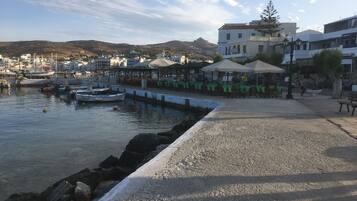 A coastal town with a marina, outdoor seating areas, and buildings with balconies.