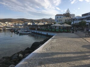 A coastal town with a marina, outdoor seating areas, and buildings with balconies.