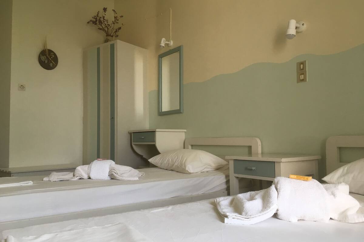 A hotel room with two beds, a dresser, a mirror, and a wall-mounted light fixture.