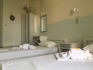 A hotel room with two beds, a dresser, a mirror, and a wall-mounted light fixture. - Afrodite Hotel (Tinos)