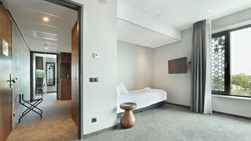 Una habitación de hotel moderna con cama, televisor y ventana con cortinas.
