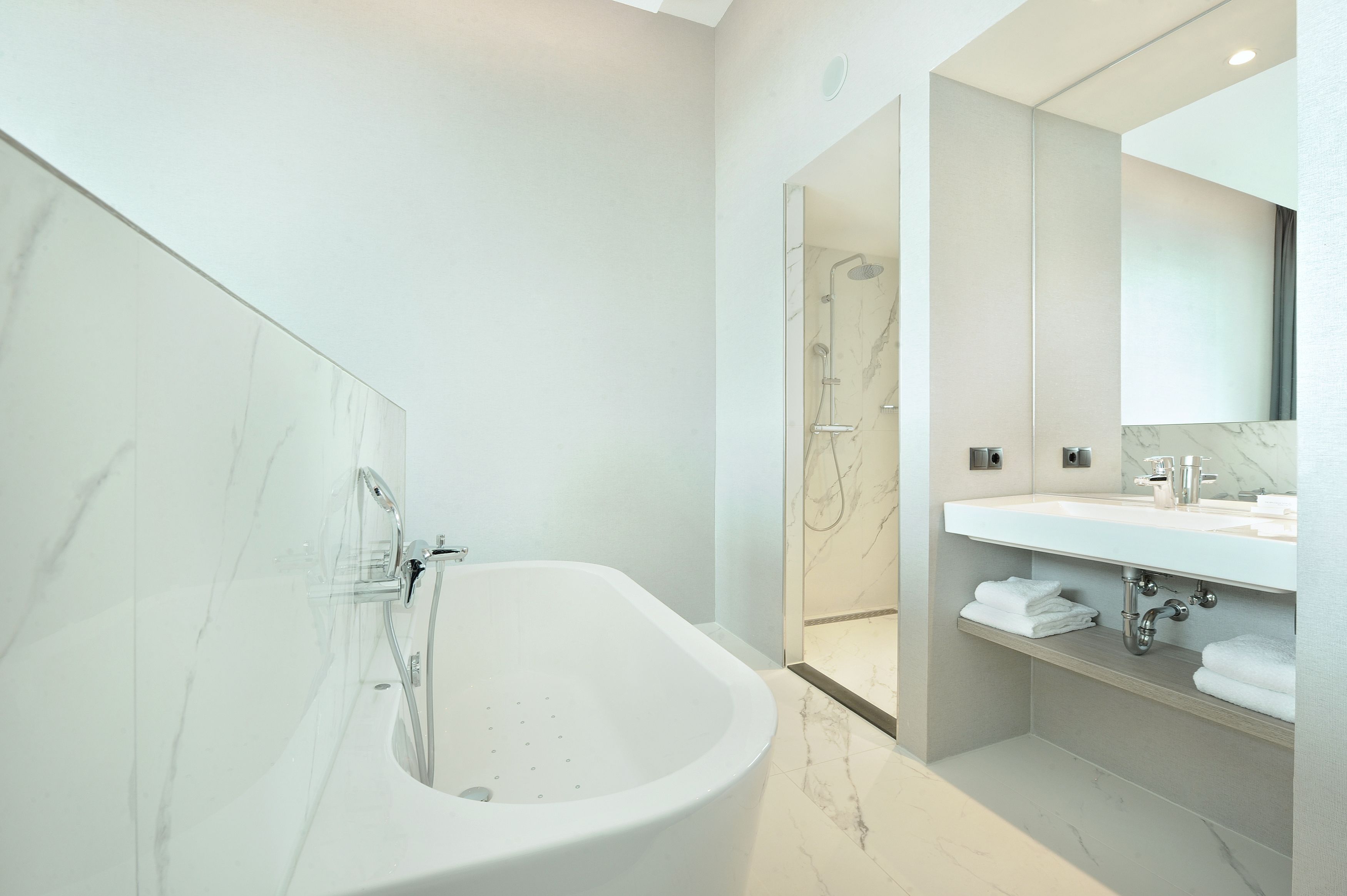 A modern bathroom with a freestanding bathtub, a walk-in shower, and a vanity with a mirror.