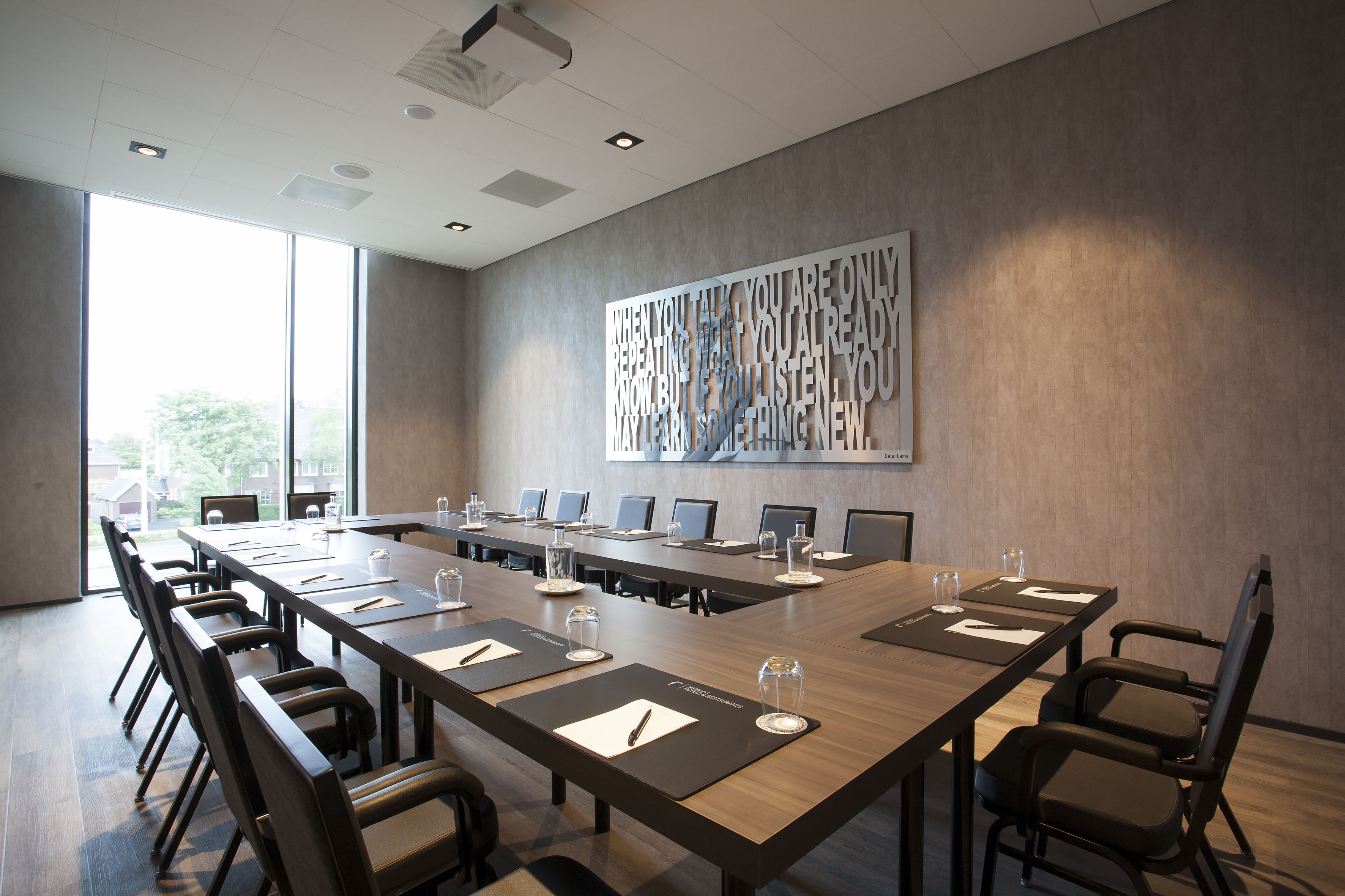 A conference room with a long table, chairs, and a large abstract art piece on the wall.