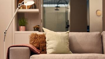 Un salon moderne avec un canapé, une lampe sur pied et une bibliothèque agrémentée d’objets décoratifs.