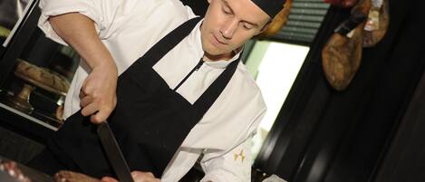 A chef slicing meat at a counter.