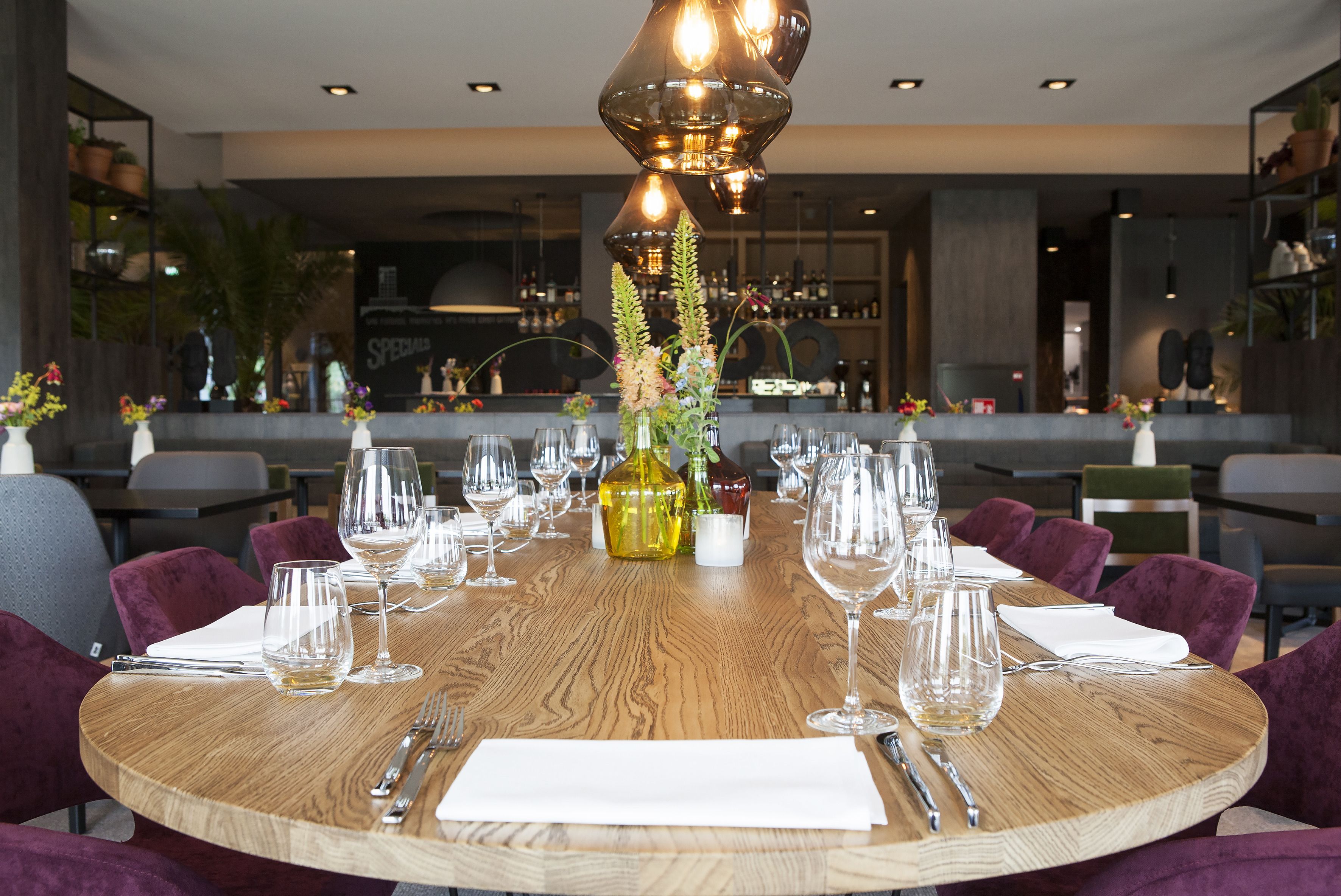 A round dining table set with wine glasses, cutlery, and a centerpiece.