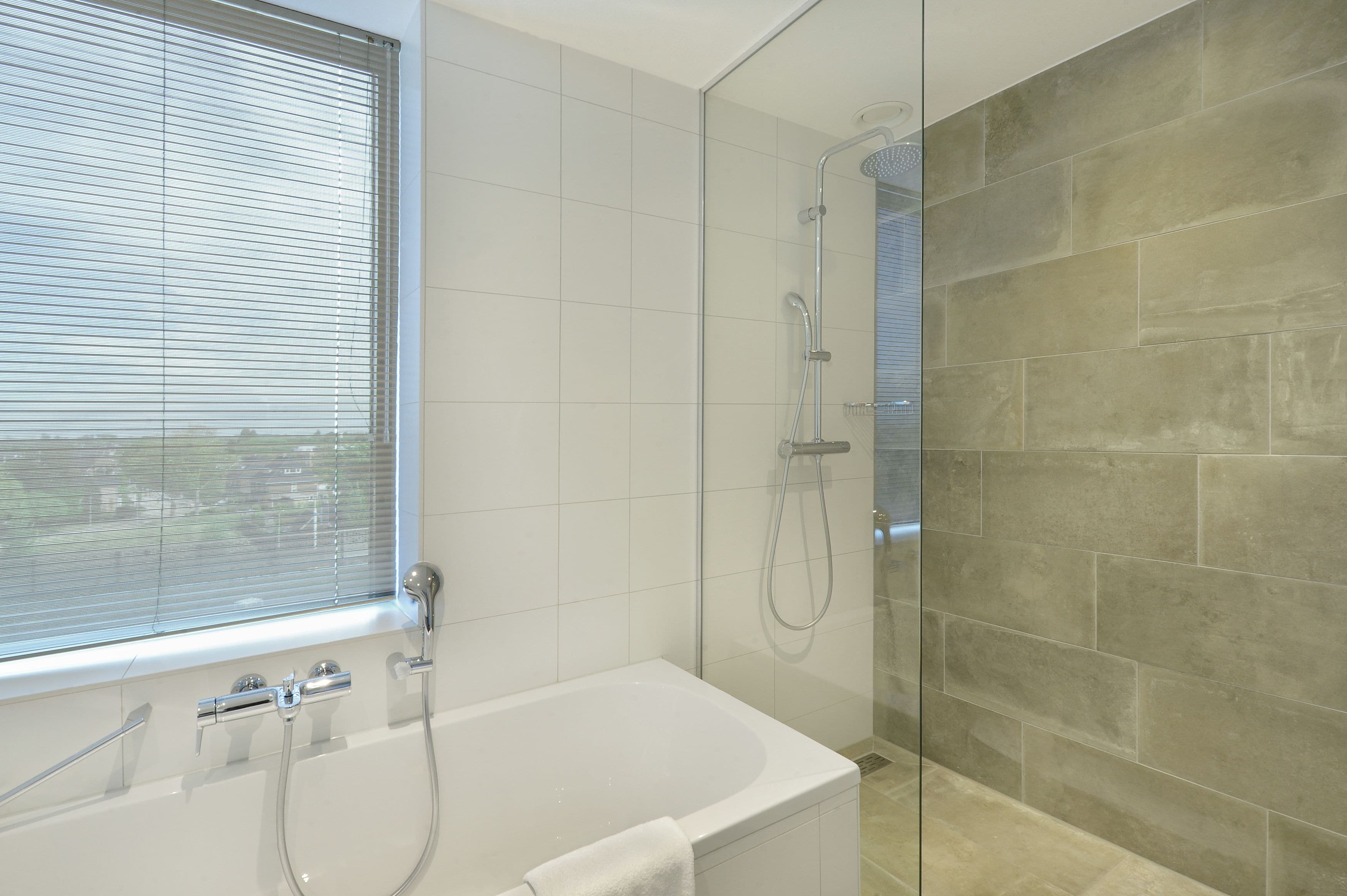 Un bagno moderno con vasca, doccia e una grande finestra.