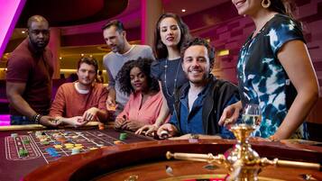 Un grup de persones a una taula de casino amb una ruleta i fitxes.