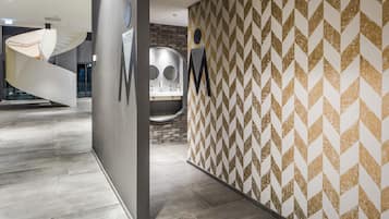 Um interior moderno com escada em espiral, parede estampada e um aviso com a palavra 'HERE'.