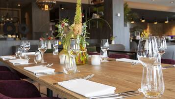 A long wooden dining table set with multiple wine glasses, cutlery, and white napkins.