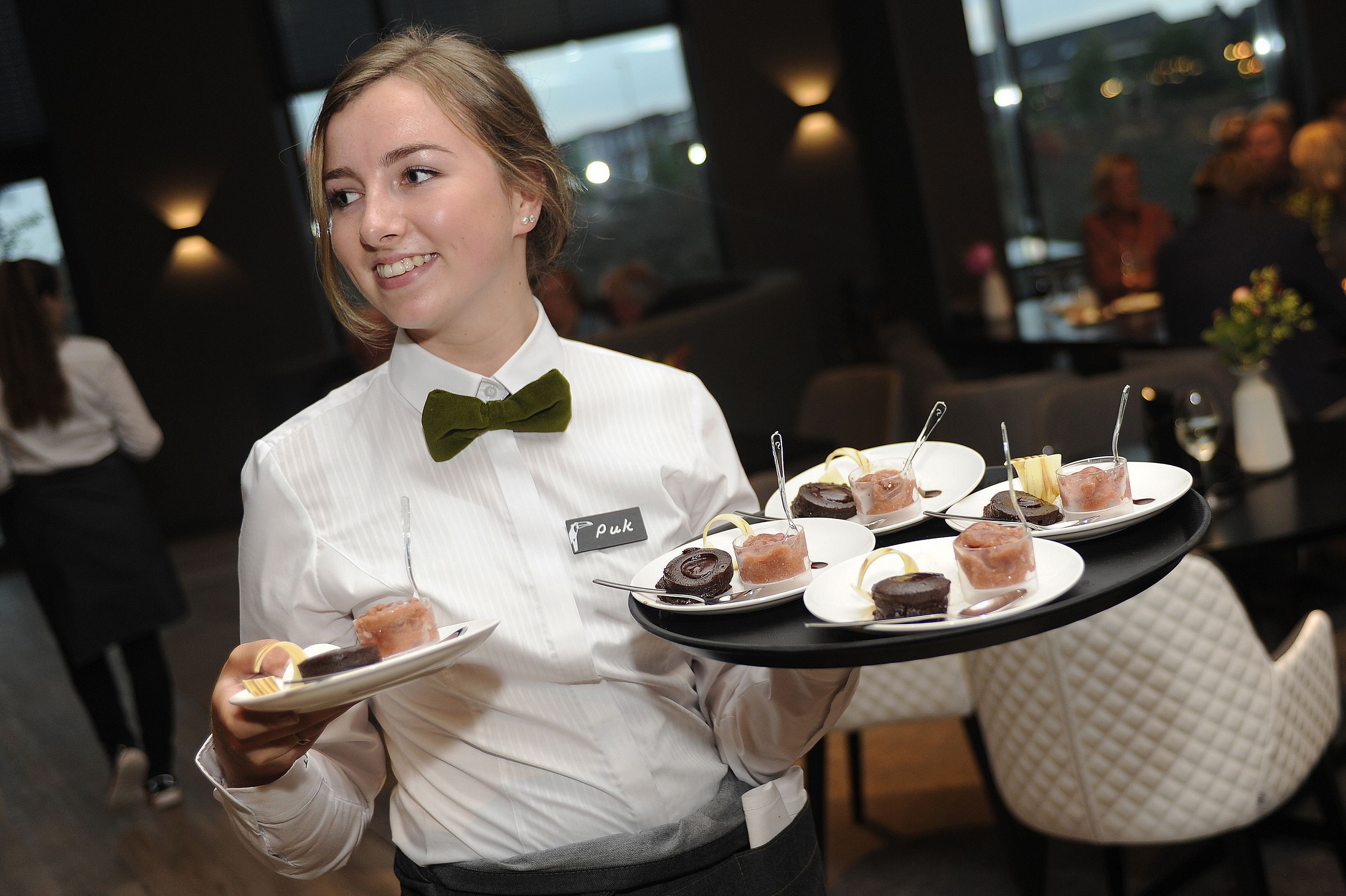 A server holding a tray with various desserts.