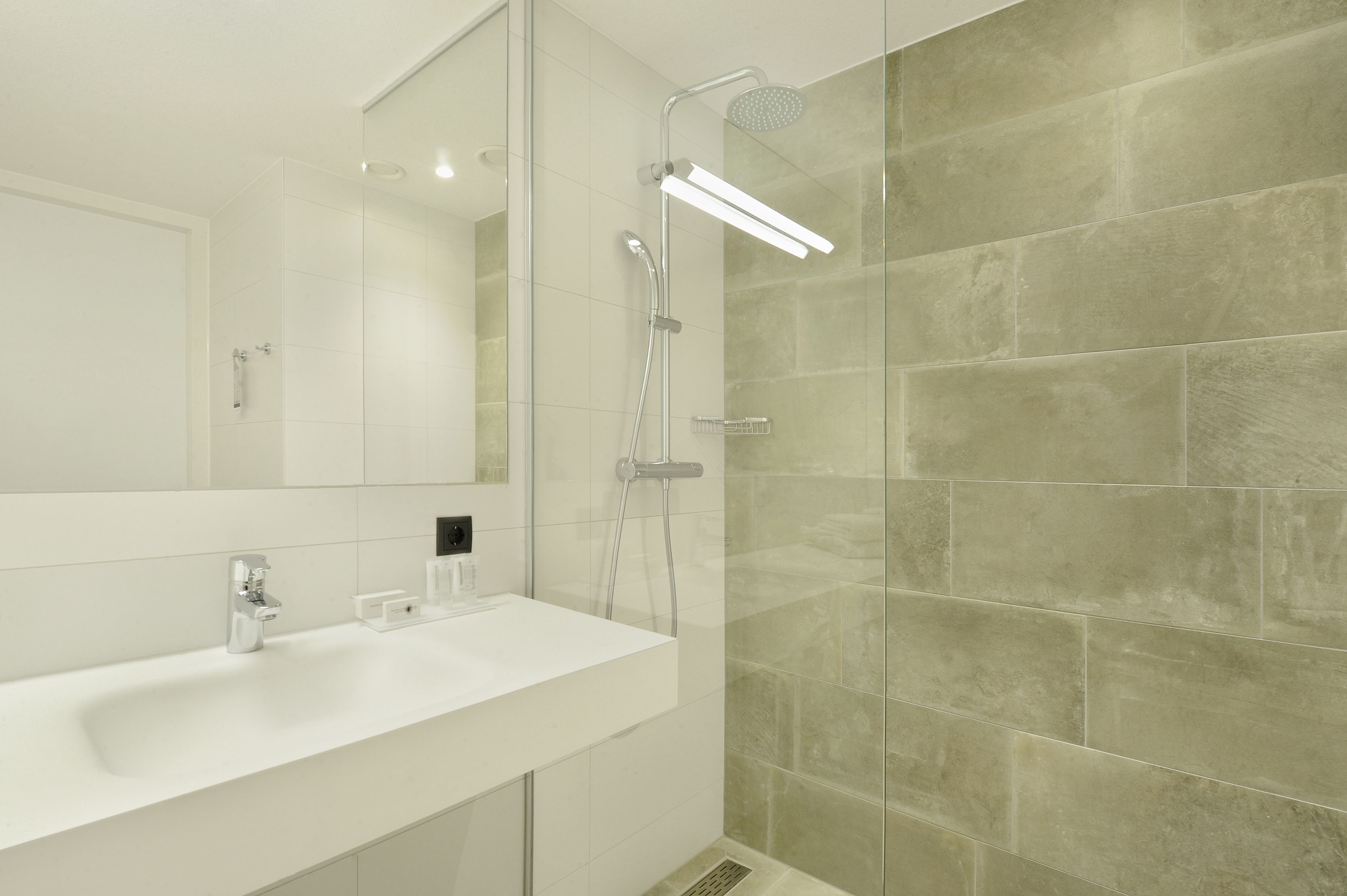 A modern bathroom with a white sink, a large mirror, and a glass shower enclosure.