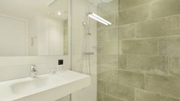 A modern bathroom with a white sink, a large mirror, and a glass shower enclosure.
